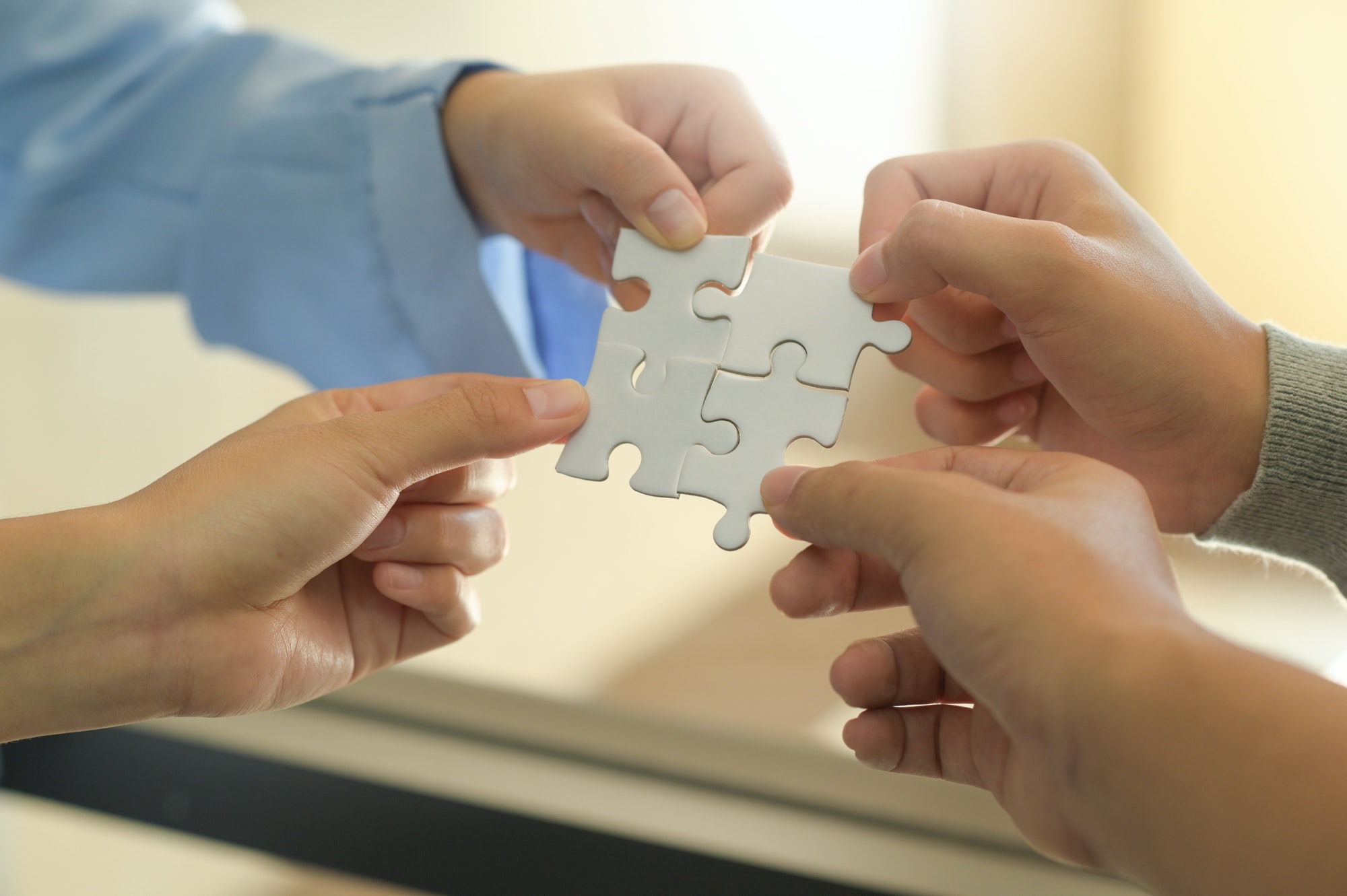 Group of businessmen holding white jigsaw puzzle pieces.