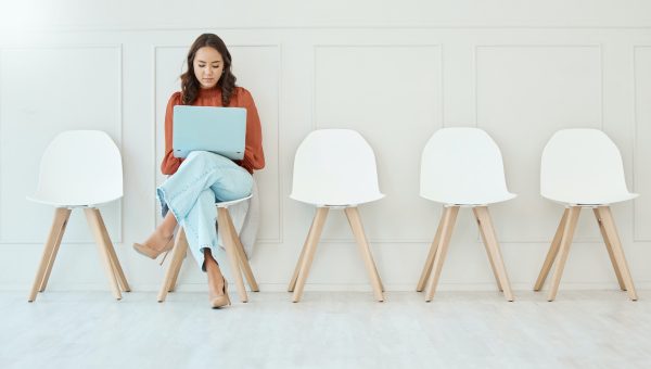 Young asian woman using laptop while sitting and waiting in line on a chair for interview. Candidat